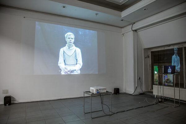 projection showing a man with white hair screened on a wall